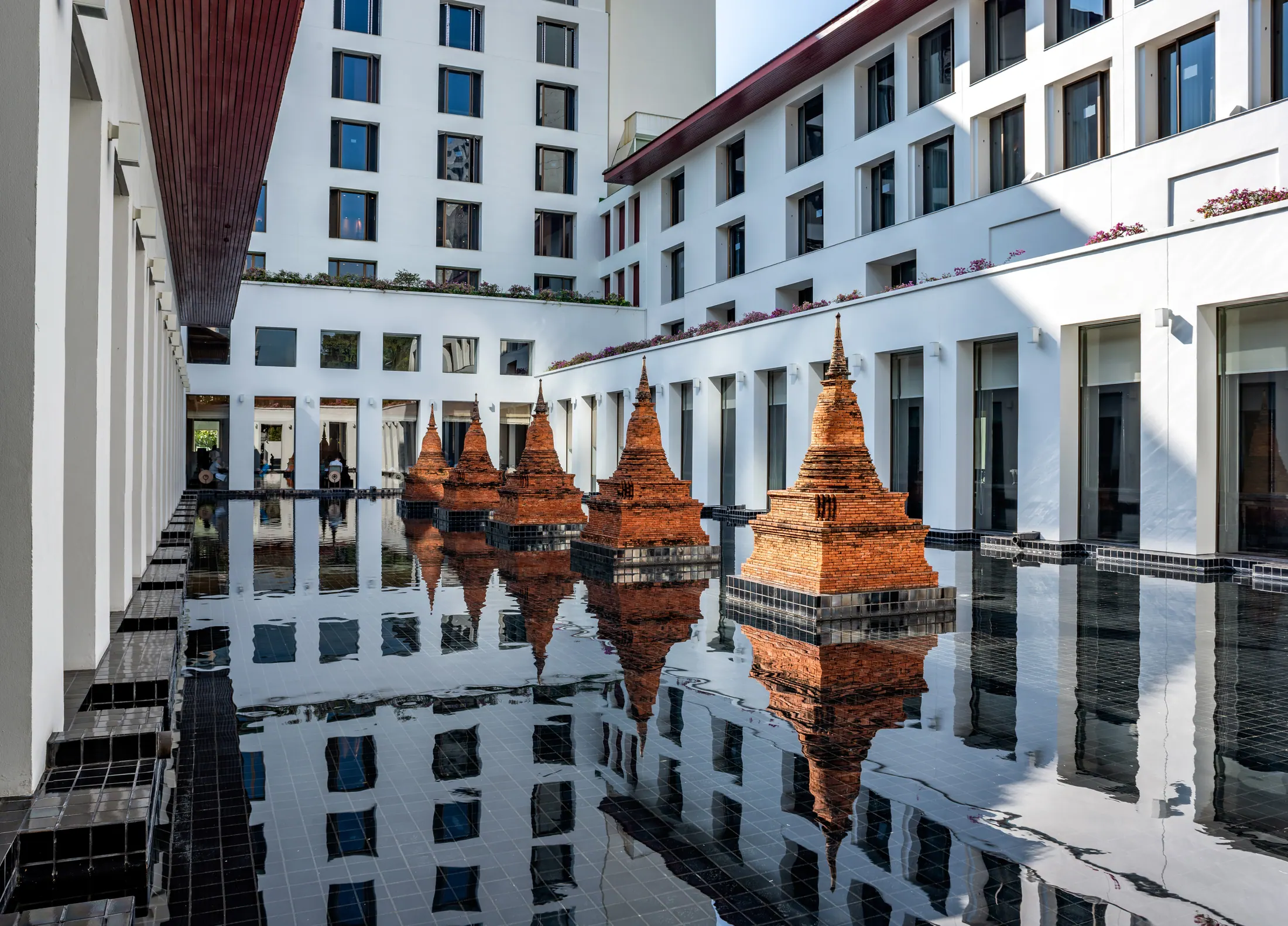 The Sukhothai Bangkok courtyard with chedi-inspired brickwork reflected in a lotus pond